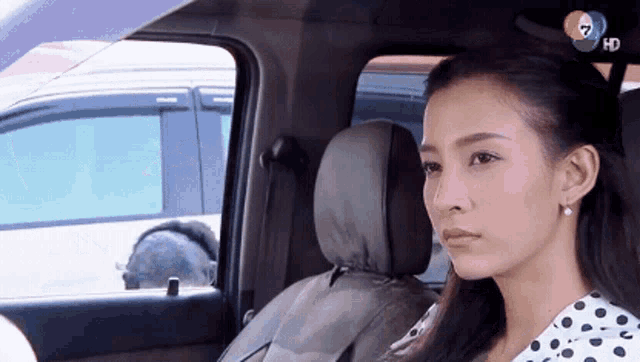 a woman is sitting in the back seat of a car with the number 7 on the bottom left