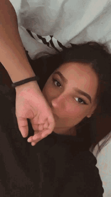 a woman laying on a bed with her hand on her face .