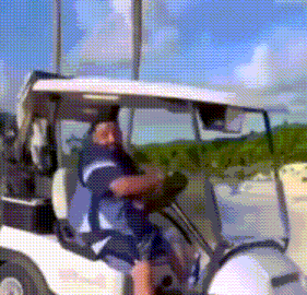 a man in a blue and white shirt is driving a golf cart .
