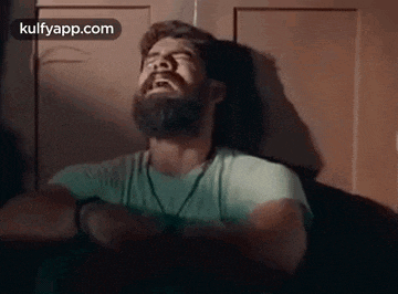 a man with a beard is leaning against a wall with his eyes closed .