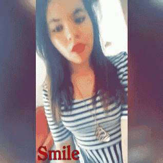 a woman in a striped shirt is smiling with the word smile in red
