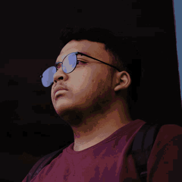 a man wearing glasses and a red shirt has the word ada on his head