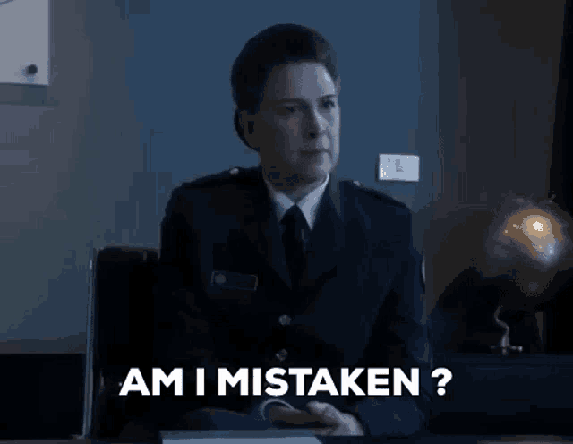 a woman in a police uniform is sitting at a desk and talking to someone .