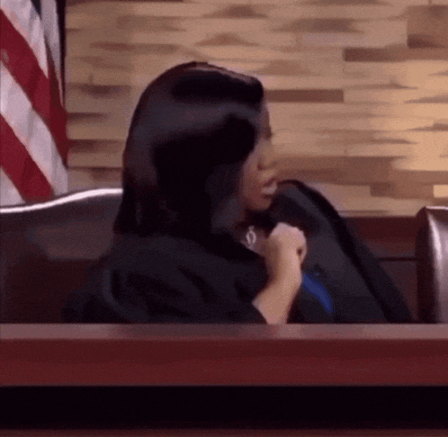 a woman in a judge 's robe sits in a courtroom