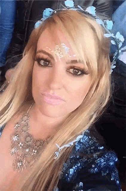 a blonde woman wearing a blue sequined dress and a flower crown on her head