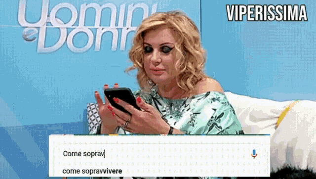 a woman is sitting on a couch looking at her phone with the words viperissima written above her