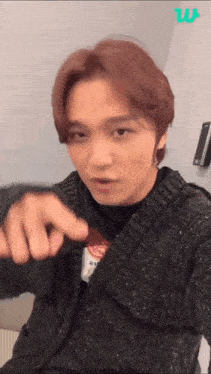 a young man in a black sweater is pointing at something