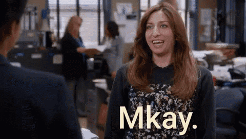 a woman is smiling while talking to a man in an office and the word mkay is on the screen .