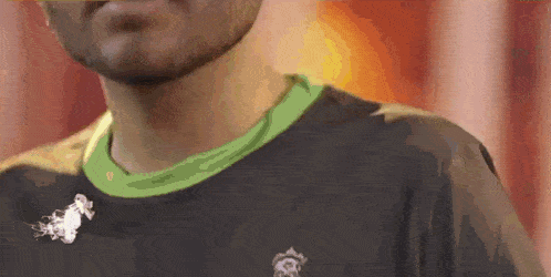 a man with a beard is wearing a black shirt with a green collar and smoke coming out of it .
