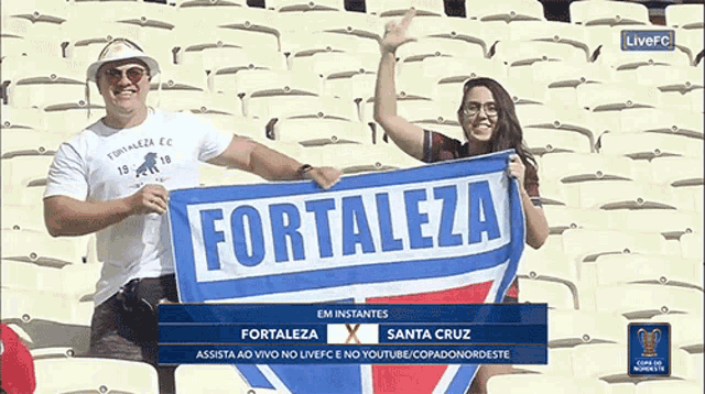a man and a woman holding a fortaleza flag in a stadium