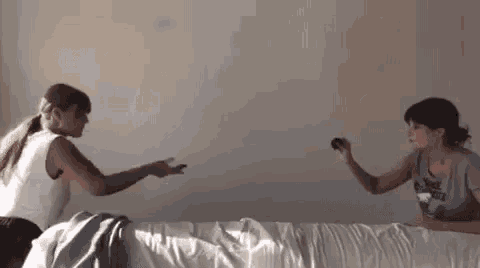 two women are standing next to each other on a bed playing a game .