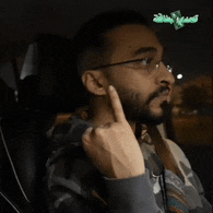 a man with glasses is giving the middle finger in a car