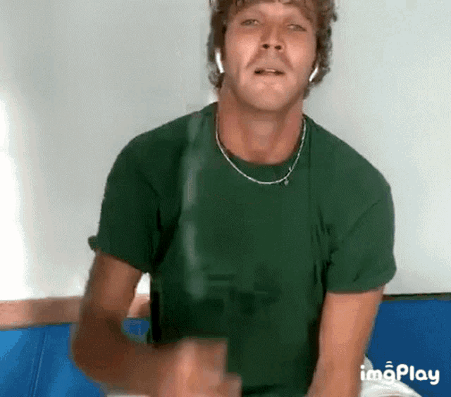 a man wearing headphones and a green shirt is sitting on a blue couch .