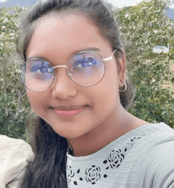 a young girl wearing glasses and a gray shirt is smiling