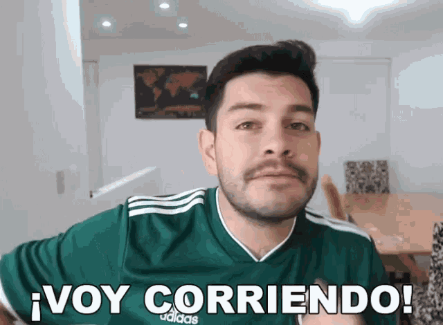 a man with a beard wearing a green adidas shirt says " voy corriendo "