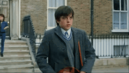 a boy in a suit and tie is walking down a sidewalk