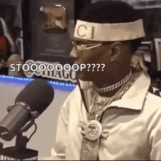 a man is sitting in front of a microphone wearing a headband with the word gucci on it .