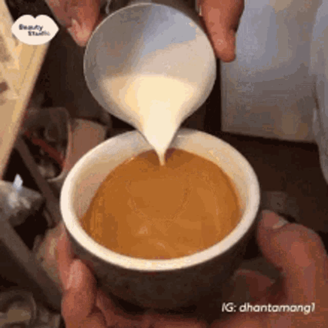 a cup of coffee with milk being poured into it .