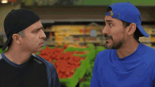 two men are standing next to each other in a grocery store