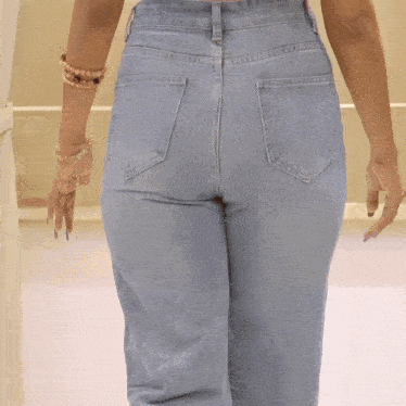 the back of a woman wearing light blue jeans and a white crop top