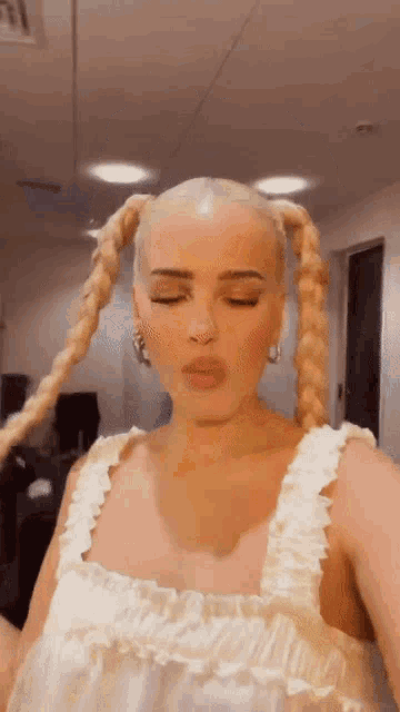 a woman with blonde hair is wearing a white dress and pigtails .