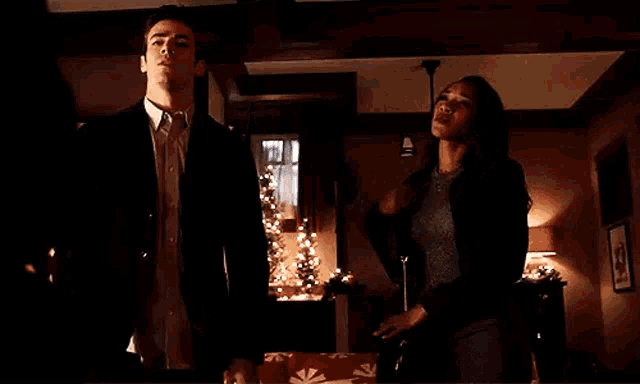 a man and a woman are standing next to each other in a room with christmas trees in the background .