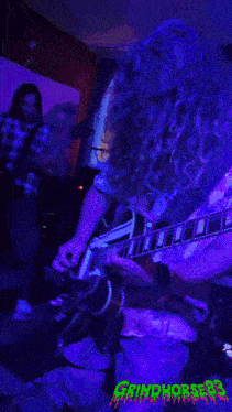 a picture of a man playing a guitar with the word grindhorses on the bottom right