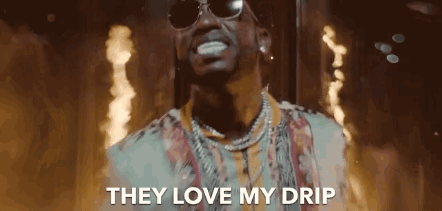 a man wearing sunglasses and a necklace says they love my drip