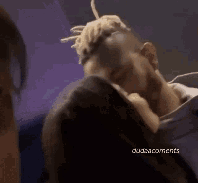 a man with dreadlocks is kissing a woman on the forehead .