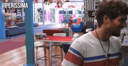 a man in a striped shirt is standing in a room with a sign that says viperissima vip on it .