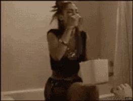 a woman is sitting in a bathtub with a roll of toilet paper in her hand .