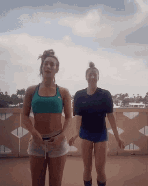two women are standing next to each other on a balcony and one is wearing a black under armour shirt