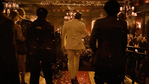 a man in a white suit is walking on a red carpet