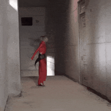 a woman in a red outfit is standing in a hallway next to a door