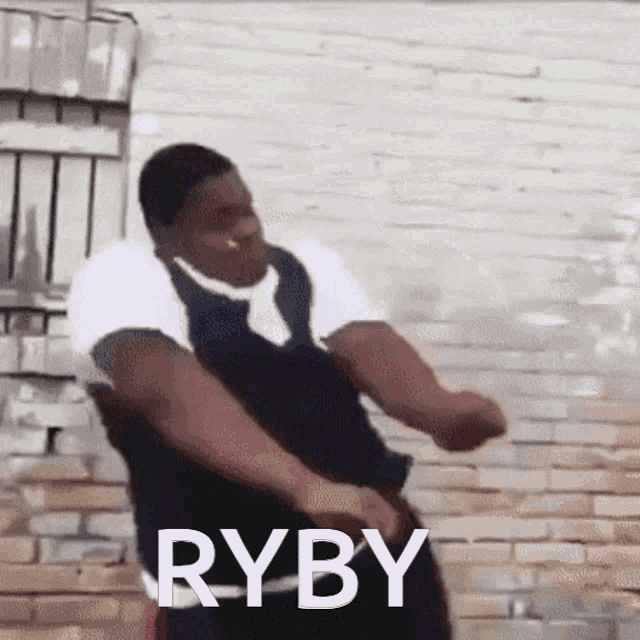 a man is dancing in front of a brick wall and the word ryby is on the bottom