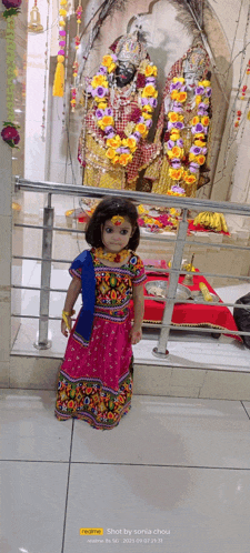a little girl in a pink dress is standing in front of a statue ..