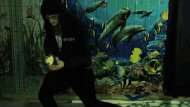 a person is dancing in front of a wall with dolphins and fish