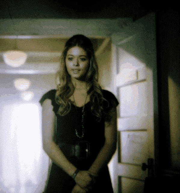 a woman in a black dress stands in a doorway