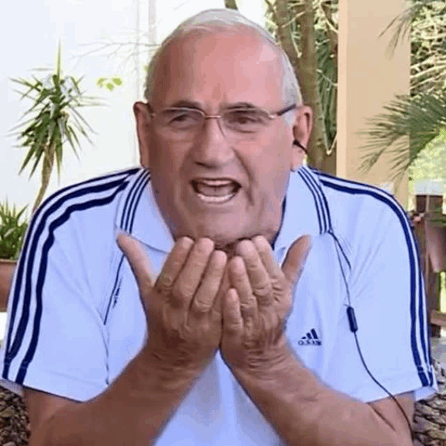 an elderly man wearing a white adidas shirt is making a funny face
