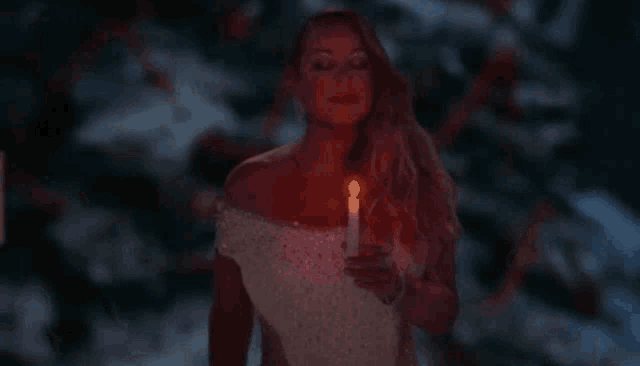 a woman in a white dress is holding a lit candle