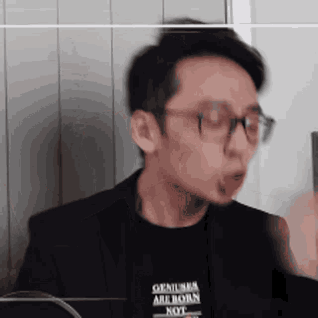 a man wearing a black shirt that says geniuses are born not