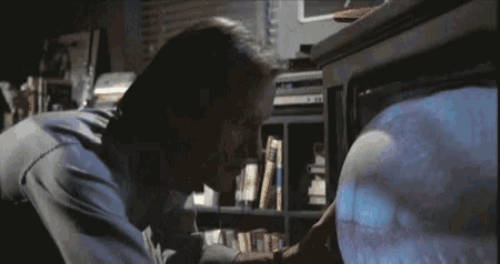 a man in a blue shirt is looking at a tv