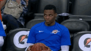 a man in a blue shirt is holding a basketball in his hands