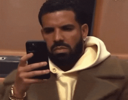 a man with a beard is looking at his cell phone