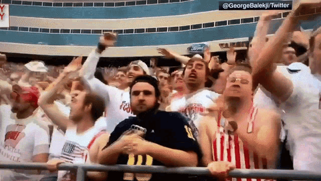a crowd of people are watching a game and one of them is wearing a shirt that says ford