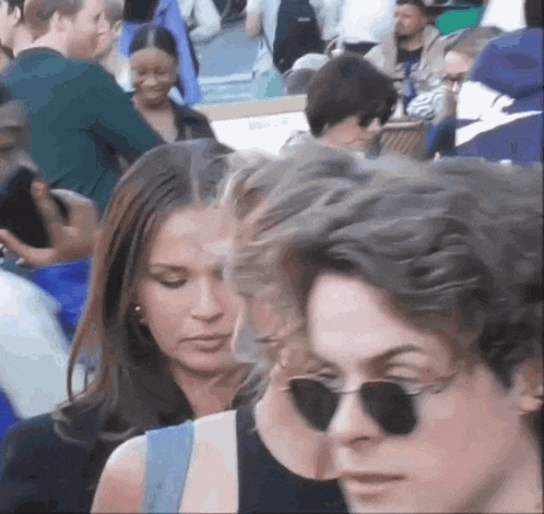 a group of people standing in a crowd wearing sunglasses