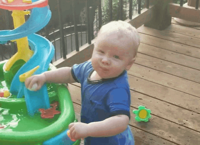 a little boy playing with a water toy on a wooden deck