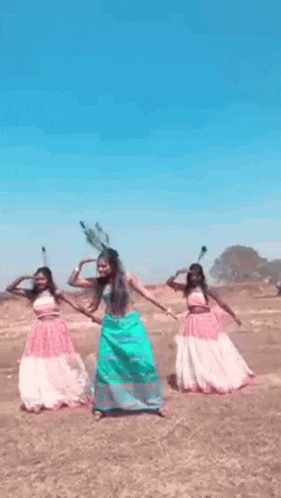 a group of women are dancing in a field with feathers on their heads .