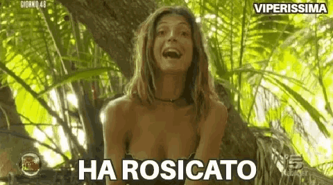 a woman in a bikini is standing in the jungle and laughing .