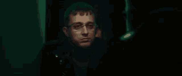 a man with glasses and blood on his face is looking at another man .